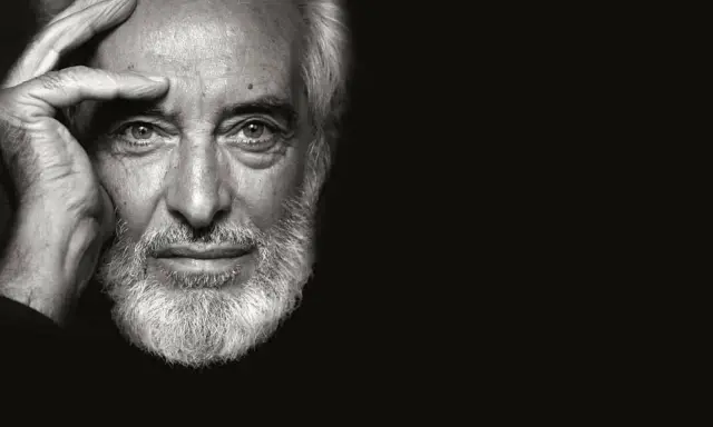 Ritratto in bianco e nero di un uomo anziano con barba bianca, mano sulla fronte. Un fotografo napoletano famoso cattura uno sguardo intenso.