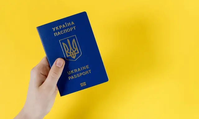 Dłoń trzyma niebieski paszport Ukrainy. Ważność dokumentu jest kluczowa dla statusu ukr do kiedy.