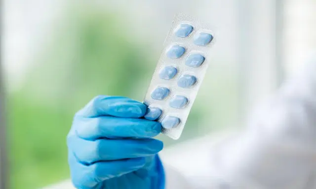 Ręka w niebieskiej rękawiczce trzyma opakowanie niebieskich tabletek. To może być alternatywa dla naturalnych suplementów na potencję.