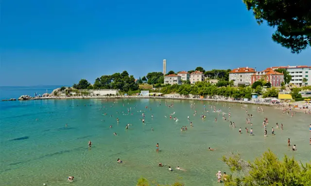 Una giornata di sole sulle spiagge Croazia, con gente che nuota e si rilassa nell'acqua cristallina.