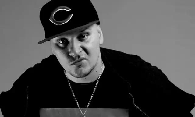 Mroczny ruby raper w czapce z daszkiem i łańcuchem, zamyślony.
