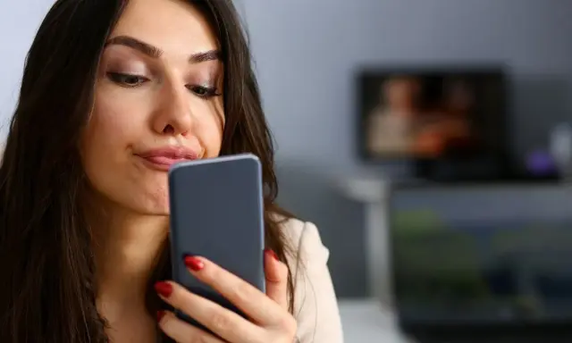 Zastanawia się, czy muszę odbierać telefon od ojca dziecka. Wyraz twarzy sugeruje niepewność.
