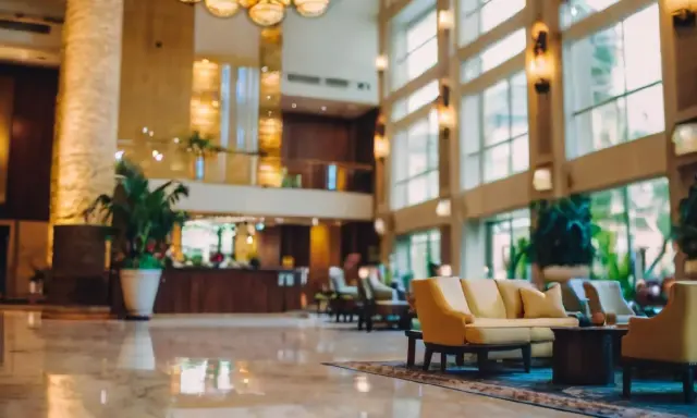 Eleganckie lobby hotelu 10 gwiazdkowego z marmurową podłogą, wygodnymi sofami i bujną roślinnością.