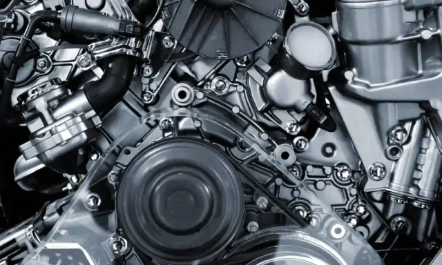 Detalle de un motor de cuatro tiempos, con correas, poleas y componentes metálicos pulidos.