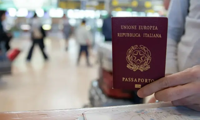Włoski paszport w dłoni, gotowy do podróży po Europie. To idealny sposób na wakacje bez paszportu, gdy podróżujesz w strefie Schengen.