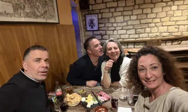 Ambiance chaleureuse dans la taverne médiévale Paris. Quatre amis partagent un repas convivial, entre rires et dégustations.