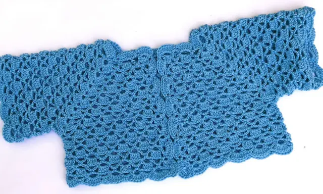 Bolero crochet azul con un delicado patrón de escamas y borde ondulado.
