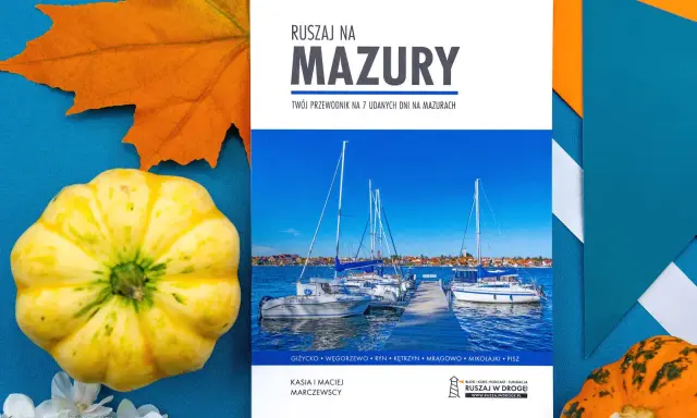 Przewodnik "Ruszaj na Mazury" z widokiem na żaglówki i jesienne dekoracje. Idealny pomysł na mazury na weekend.