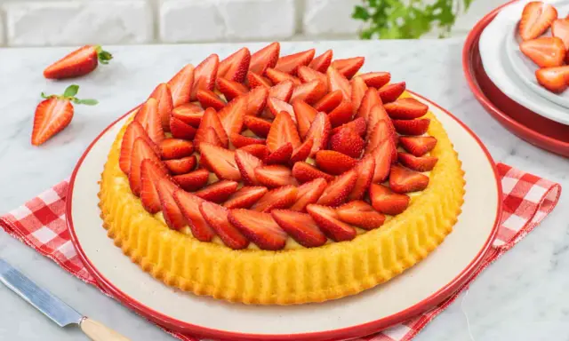 Una deliziosa crostata morbida alle fragole, con la sua base dorata e un abbondante strato di fragole fresche affettate.