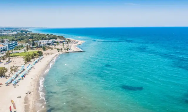 Piękna plaża na wyspie Kos z turkusową wodą, leżakami i palmami. Idealne miejsce na wakacje.