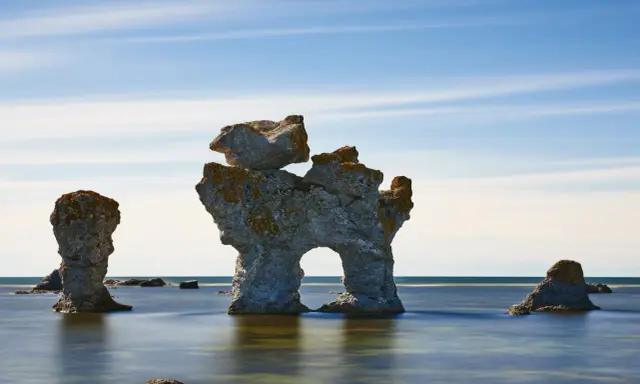 Raukar i havet vid Fårö, Gotland. En fantastisk vy att se på Gotland, med stenformationer som reser sig ur det blå vattnet under en molnig himmel.