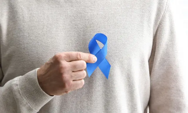 Mężczyzna trzyma niebieską wstążkę symbolizującą świadomość raka prostaty. Rozważamy usunięcie prostaty skutki.