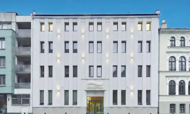Nowoczesny, biały budynek kliniki Balticmed w Szczecinie z podświetlanym logo i oknami.