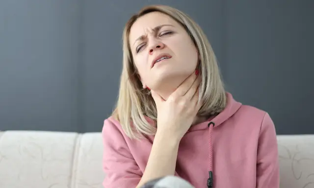 Kobieta z bólem szyi, próbująca ćwiczenia na porażenie fałdu głosowego.