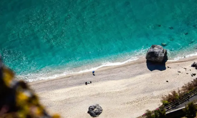 Spiaggia dorata e mare turchese in Liguria. Un pescatore solitario ammira la bellezza del **liguria mare**.