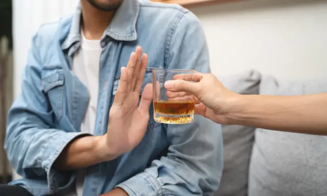 Mężczyzna odmawia alkoholu, symbolizując dobrowolne leczenie odwykowe i nowy początek.