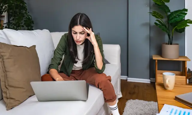 Introwertyczka skupiona na pracy przy laptopie na kanapie. Idealna praca dla introwertyka, gdzie można pracować w spokoju.