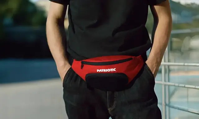 Męska nerka w kolorze czerwonym, z napisem "PATRIOTIC", noszona na wysokości bioder. Stylowy dodatek, który pokazuje, jak nosić nerkę męską.