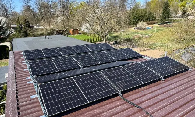 Panele fotowoltaiczne na dachu. Rozważasz, jak obniżyć napięcie w sieci fotowoltaika? Instalacja wygląda na gotową do pracy.