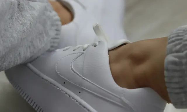 Białe sneakersy z szarym swetrem. Dowiedz się, jak zabezpieczyć białe buty, by długo wyglądały jak nowe.