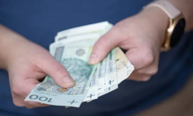 Dłonie trzymające polskie banknoty 100 zł. Czy to nagroda, czy może podatek od nagrody?
