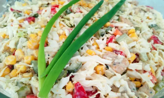 Pyszna sałatka gyros mieszana z kurczakiem, kukurydzą, papryką i ogórkiem, udekorowana szczypiorkiem.