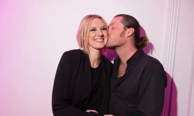 Sanna Nielsen ler när en man med hästsvans ger henne en puss på kinden.