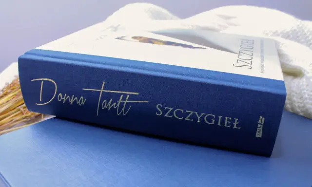 Granatowa okładka książki "Szczygieł" Donny Tartt z wytłoczonym złotym napisem.