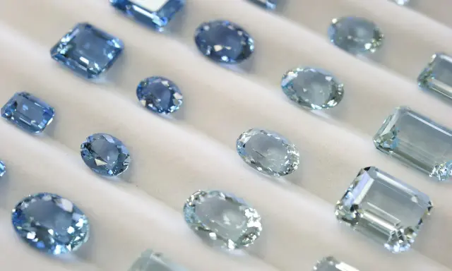 Collezione di acquamarine con taglio smeraldo e altre forme, che brillano su un morbido sfondo bianco.