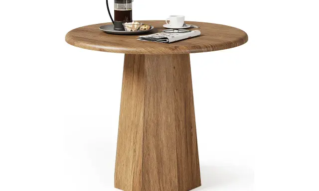 Ett runt, träfärgat litet slagbord med en kaffepress, en kopp och en tidning.