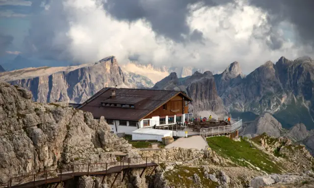 Rifugio alpino in Alto Adige, con sentiero metallico e imponenti vette sullo sfondo.
