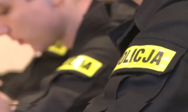 Zbliżenie na rękawy mundurów policyjnych z żółtymi naszywkami "POLICJA".