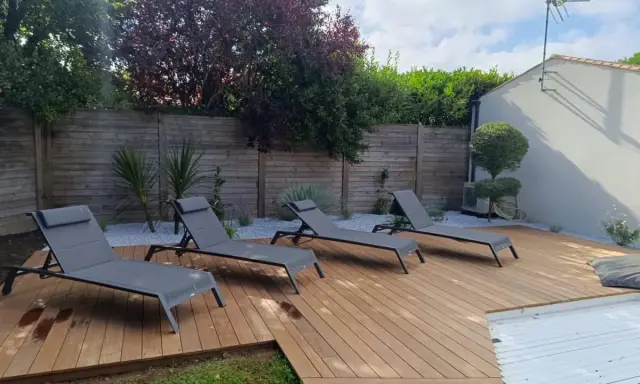 Aménagement terrasse en bois avec chaises longues invitant à la détente. Un espace extérieur parfait pour profiter du soleil.