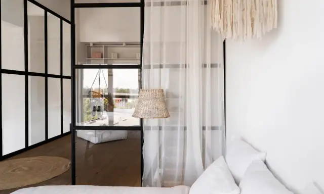 Verre et rideaux pour séparer une petite chambre en deux, créant des espaces distincts et lumineux.