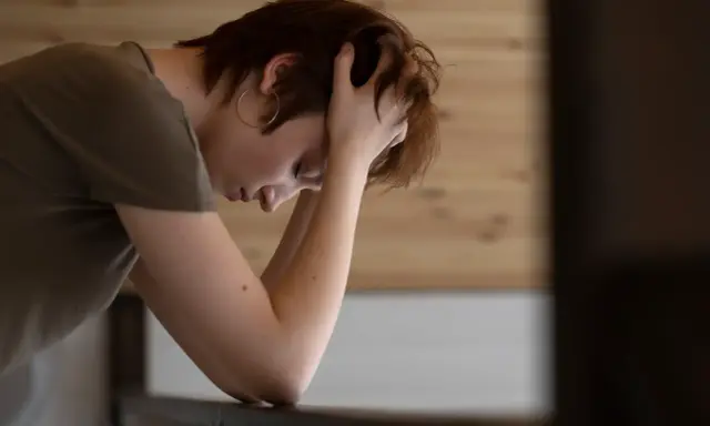 En person med händerna i håret, ser nedåt. Kanske en bild som visar hur man kan tänka kring hur minskar man stress.