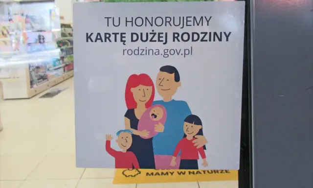 Plakat informujący o honorowaniu Karty Dużej Rodziny z rysunkiem rodziny.