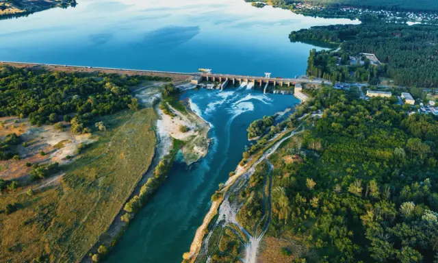 Luftaufnahme eines Laufwasserkraftwerks, das die Vorteile erneuerbarer Energie zeigt.