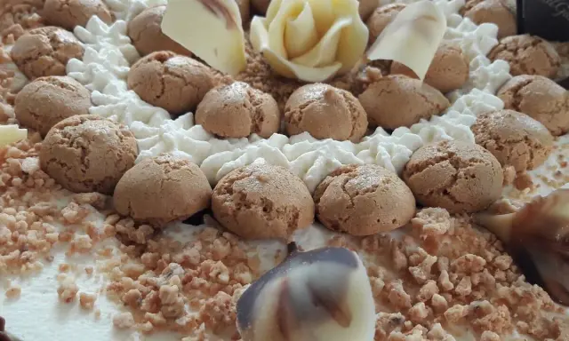 Torta decorata con biscotti, panna montata, cioccolato bianco a forma di rosa e granella. Il re del gelato trama, un capolavoro da gustare.