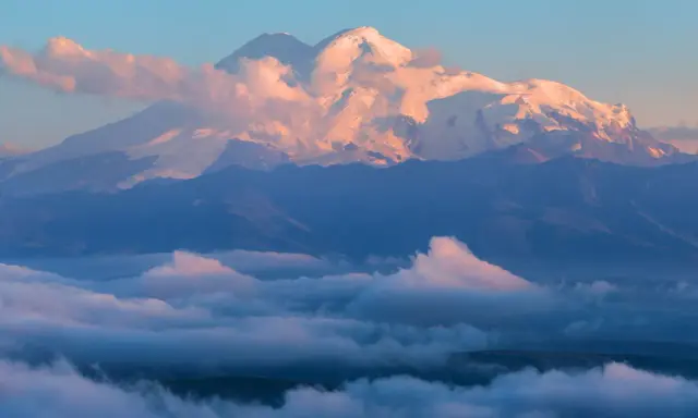 Elbrus, najwyższy szczyt Kaukazu, lśni w blasku wschodzącego słońca, otoczony morzem chmur.