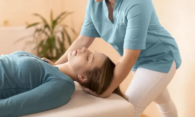 Fizjoterapeuta delikatnie masuje mięsień obojczykowo sutkowy pacjentki, przynosząc ulgę.