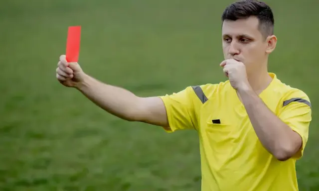 Arbitre siffle et brandit un carton rouge, signalant une faute grave. Il faut bien conjuguer "enfreindre" pour éviter ce genre de situation.