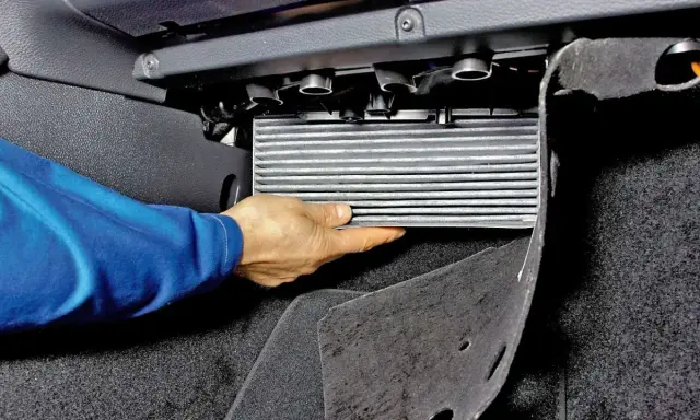 Wymiana filtra kabinowego Skoda Octavia 2. Dłoń wyjmuje filtr z obudowy pod deską rozdzielczą.
