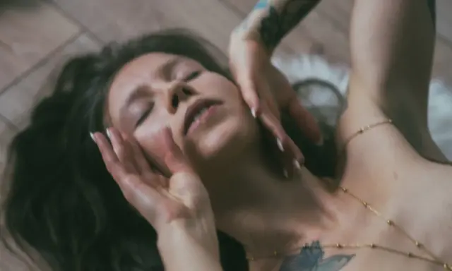 Lilith w byku, z zamkniętymi oczami, dłońmi na twarzy, leży na drewnianej podłodze.