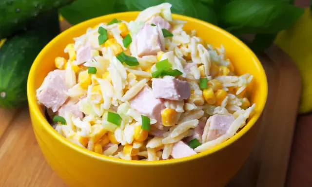 Pyszna sałatka z makaronem orzo, kawałkami szynki, kukurydzą i szczypiorkiem, podana w żółtej misce.