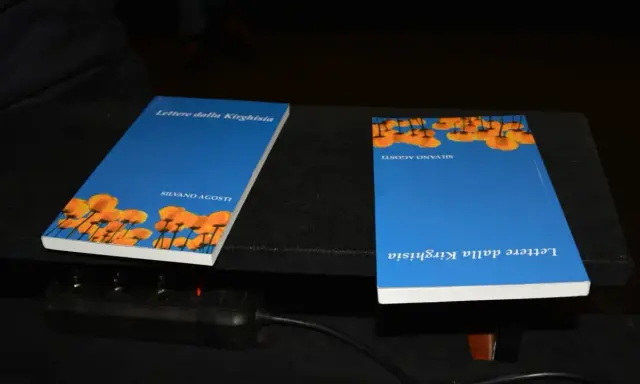 Due libri "Lettere dalla Kirghisia" di Silvano Agosti, con copertina blu e fiori arancioni.