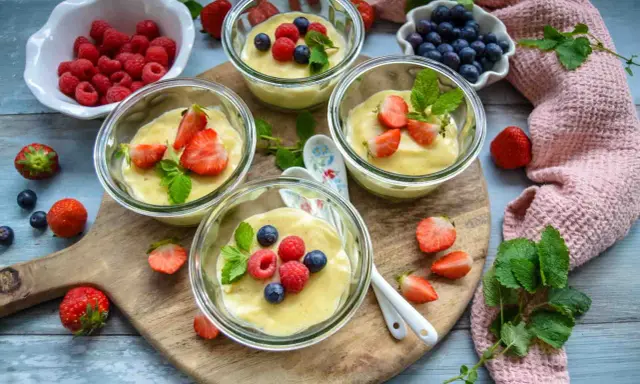 Vier Gläser mit selbstgemachtem Pudding, garniert mit frischen Beeren und Minze. Ein Genuss für Augen und Gaumen!