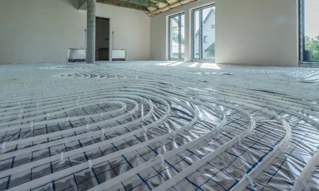 Rozłożone rury do ogrzewania podłogowego wodnego w nowym domu. Instalacja gotowa do zalania wylewką.