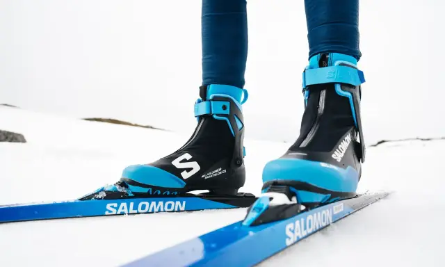 Nära bild på ett par skidpjäxor och skidor i klassisk stil, redo för en tur i snön.