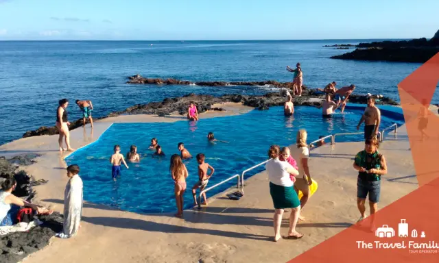 Famiglia felice alle Azzorre con bambini che nuotano in una piscina naturale.