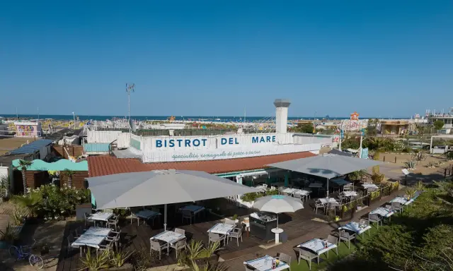 Il Bistrot del Mare a Rimini, con tavoli all'aperto e vista sulla spiaggia affollata, offre specialità romagnole.